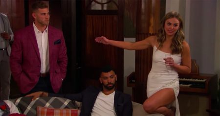 Hannah, looking amazing in a white dress, angrily points to Luke P. Dustin sits on a couch in between them.