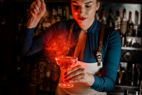 Woman bartender mixing a glowing red drink