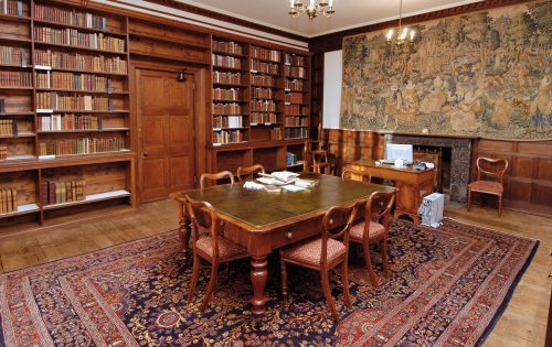 The Library Reading Room with table, chairs, fireplace, and so many books