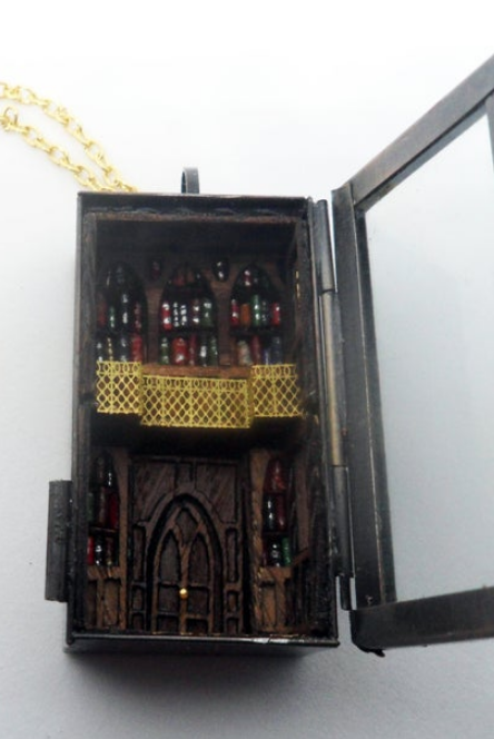 A tiny gothic library with arched doors and bookshelves and a tiny lattice gallery inside a miniature locket