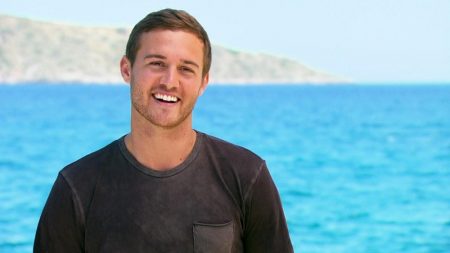 Peter smiles as he stands in front of a turquoise blue sea