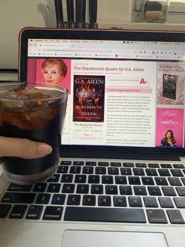 A glass of rum and coke next to the review of The Blacksmith Queen