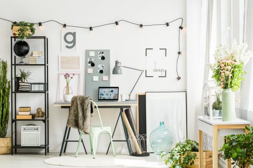 Cozy office room in Scandinavian style with plants everywhere and a green metal chair. Home office design concept