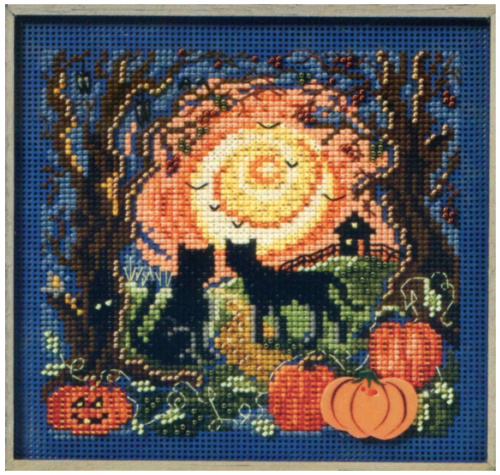 A beaded and cross stitched picture of two cats, a bright orange sunset surrounded by trees and pumpkins