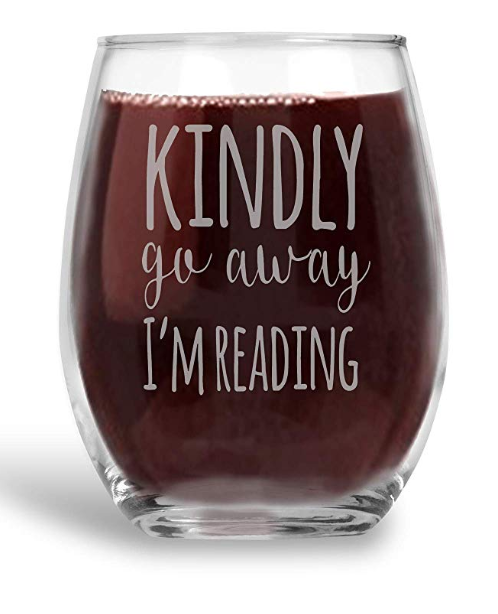 A stemless wine glass that says Kindly go away I'm reading