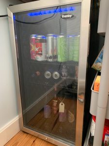 A snapshot of Amanda's beverage fridge with beer bottles, cans and tall cans lined up on the shelves