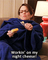 Liz Lemon wears a snuggie and eats a wedge of cheese while singing workin on my night cheese