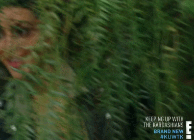 Kim Kardashian peeks around a bush