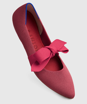 A red pointed toe flat with a brighter red fabric ribbon tied over the instep