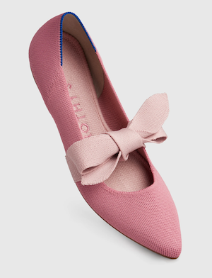 A pink pointed toe flat with a light pink fabric bow tied over the instep
