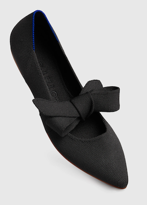 A pointed toe black flat with a black fabric ribbon tied on a bow over the instep