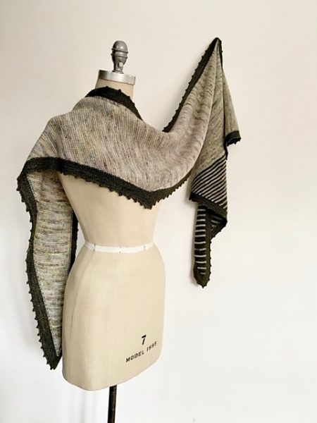 A a symmetrical shawl in an oatmeal color with a black picot border