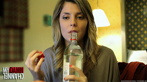 A woman drinks straight from a liquor bottle