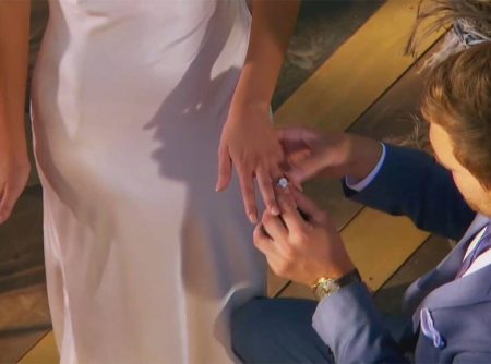 A close up of Peter putting a ring on Hannah Ann's finger