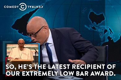 Larry Wilmore holds a steel bar labels "Extremely Low Bar" while stating that "He's the recipient of our extremely low bar award."