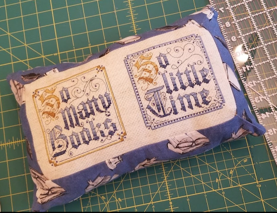 Two squares of decorative cross stitched text that read SO MANY BOOKS SO LITTLE TIME