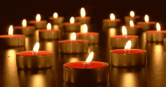 a slow looping gif of red tea light candles burning on a gold reflective surface