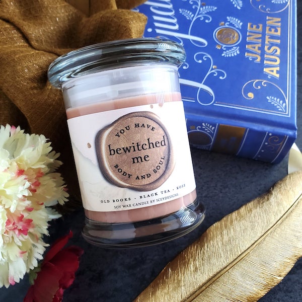 icey candle you have bewitched me body and soul a dark pink candle in a glass jar with a blue copy of pride and prejudice in the background