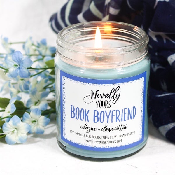 A blue candle with a label that reads novelly yours book boyfriend cologne and clean cotton