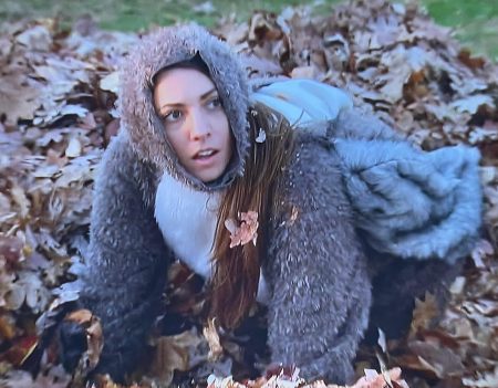 Queen Victoria dressed as a squirrel digs in a pile of leaves