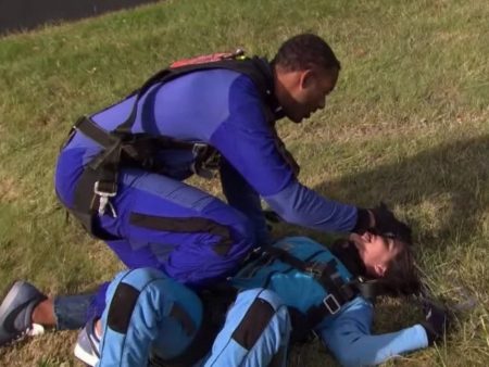 Matt leans over Rachael who is sprawled out on the grass