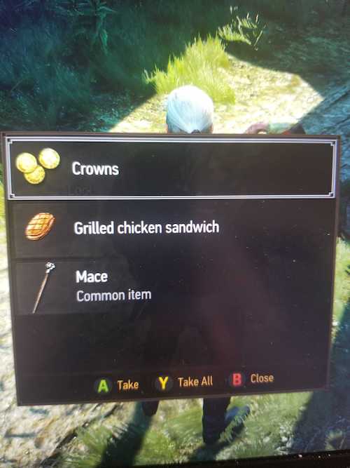 A screen cap of a moment in Witcher 3 where geralt is about to loot a dead bandit and the bandit has crowns, a grilled chicken sandwich, and a mace 