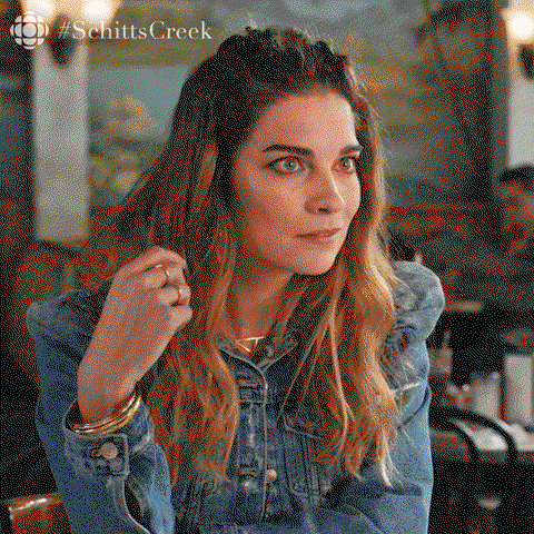 Anne from Schitt's Creek props her chin on her hands and is interested 