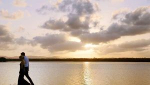 The silhouette of two figures walking on the beach at sunset