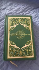 A green hardcover with gold filigree and the words The Classics of Romance in gold with extreme swirls at the top and bottom of the F framing the word