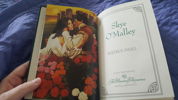 the title page with a color version of some clinch cover art of a man and woman in a weird swirl of roses about to make out in front of a castle the title page reads Skye O'Malley by Bertrice Small with the words collectors edition the classics of romance, shelton connecticut at the bottom