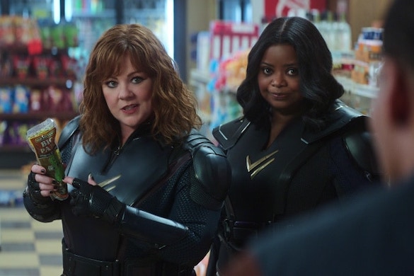 Melissa McCarthy holding a pickle in a bag in a convenience store while Spencer looks over her shoulder 