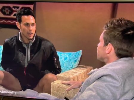 Thomas sits on a couch wearing shorts and a jacket. He has his legs spread wide open and his hands in his pockets and he looks naked from the waist down