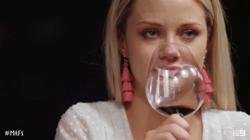 a woman rolls her eyes while drinking from a wine glass