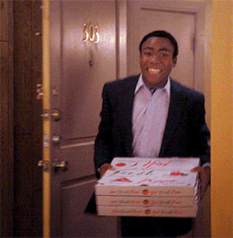 a man walks into a room carrying several pizza boxes only to find the room on fire