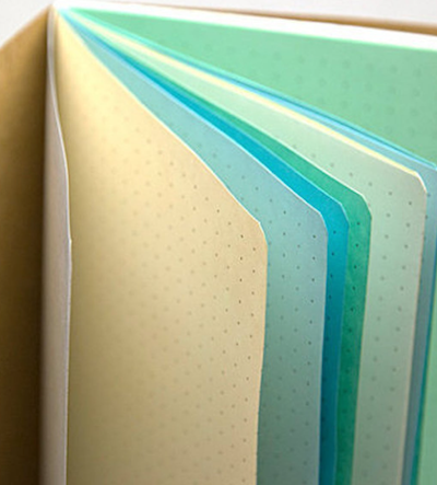 Dot grid notebook close up with paper in cream iceb lue deep blue and green