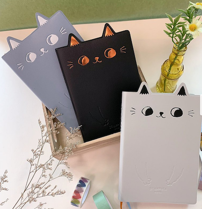 Cat Ear notebook with tiny triangular ears on the top border above a smiling cat fact