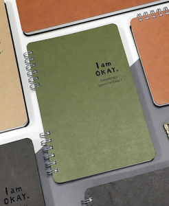 a spiral bound weekly undated planner with I AM OK on the front