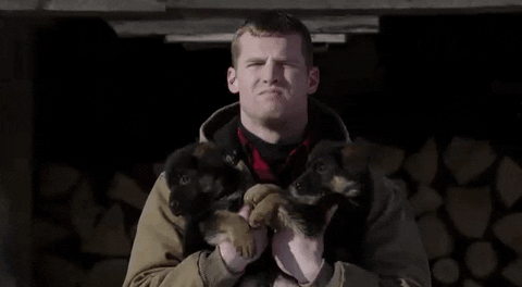 Wayne holds two puppies and says All Right