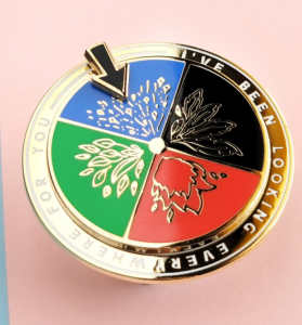 An enamel spinning pin with four seasons and materials with the words I've been looking everywhere for you around the border