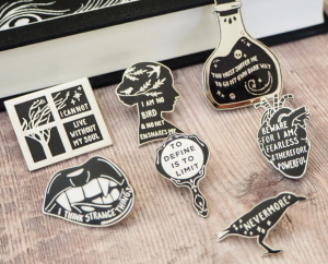 A set of seven enamel pins with quotes from classic gothic literature text