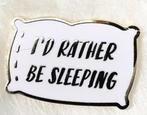 A pillow shaped enamel pin that says I'd Rather Be Sleeping