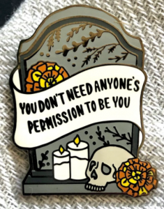 A tombstone with a banner that says You Don't need anyone's permission to be you 