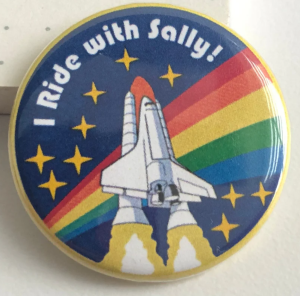 A pin with a space shuttle a rainbow and the words I RIDE WITH SALLY