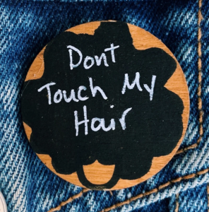 Miniature wood pin with a silhouette of a woman's hair with the words Don't Touch My Hair 