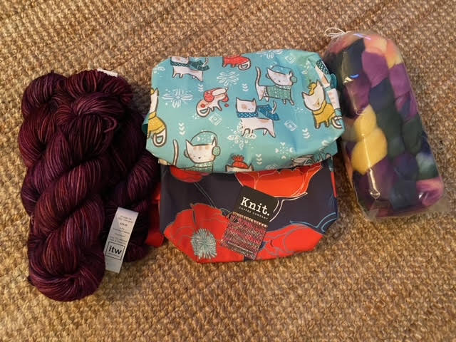 Two project bags, one with cats and one with poppies, with yarn and roving on either side