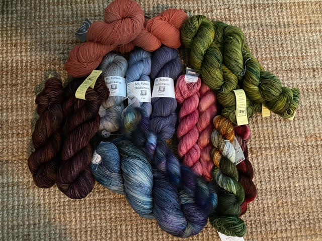 skeins upon skeins of yarn in dark red, rust, blue, pink, green and orange