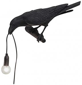 A resin raven sculpture holding a single bulb in it's beak 
