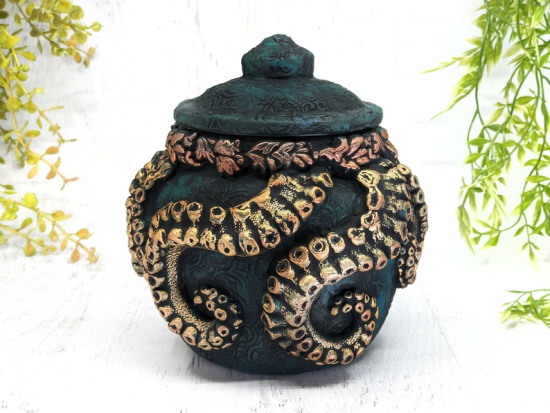 A dark green bottle with a lid with gold tentacles rwrapped around the sides 