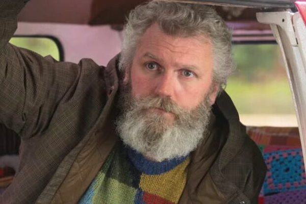 A man with a long grey beard and a knit color block sweater