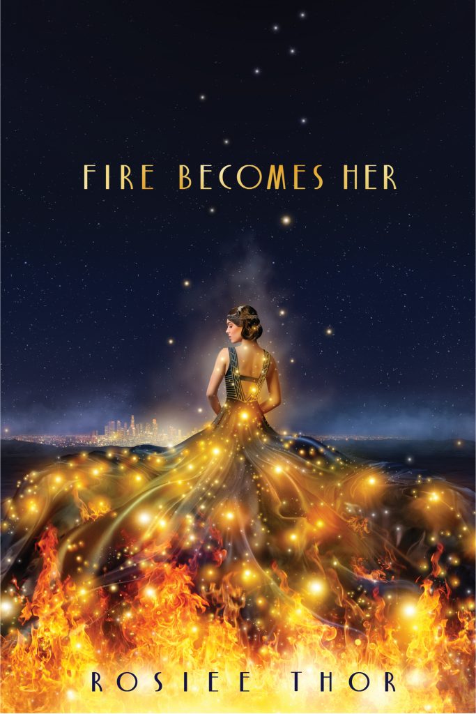 Fire Becomes Her by Rosiee Thor. A woman in a dress is facing away from her. Her dress is dark blue, but is starting to catch fire at the hem and there are sparks and flames traveling upward.